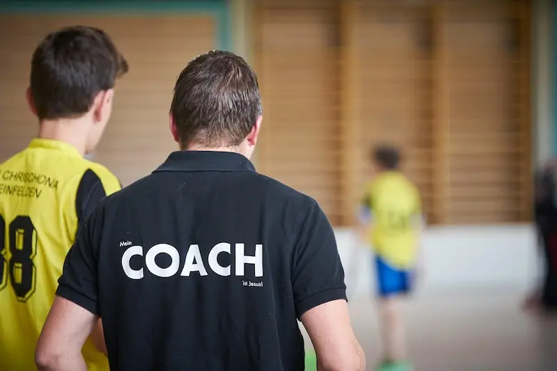 Coach sportif accompagnant ses joueurs. Il joue un rôle indispensable dans le développement des compétences relationnelles, la gestion du stress, et la cohésion de groupe.